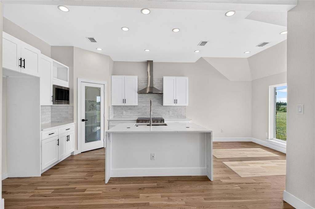 15166 FM 3133, Anna, TX 75409 Modern kitchen featuring white cabinetry, a central island with an integrated sink, and wood-finish flooring
