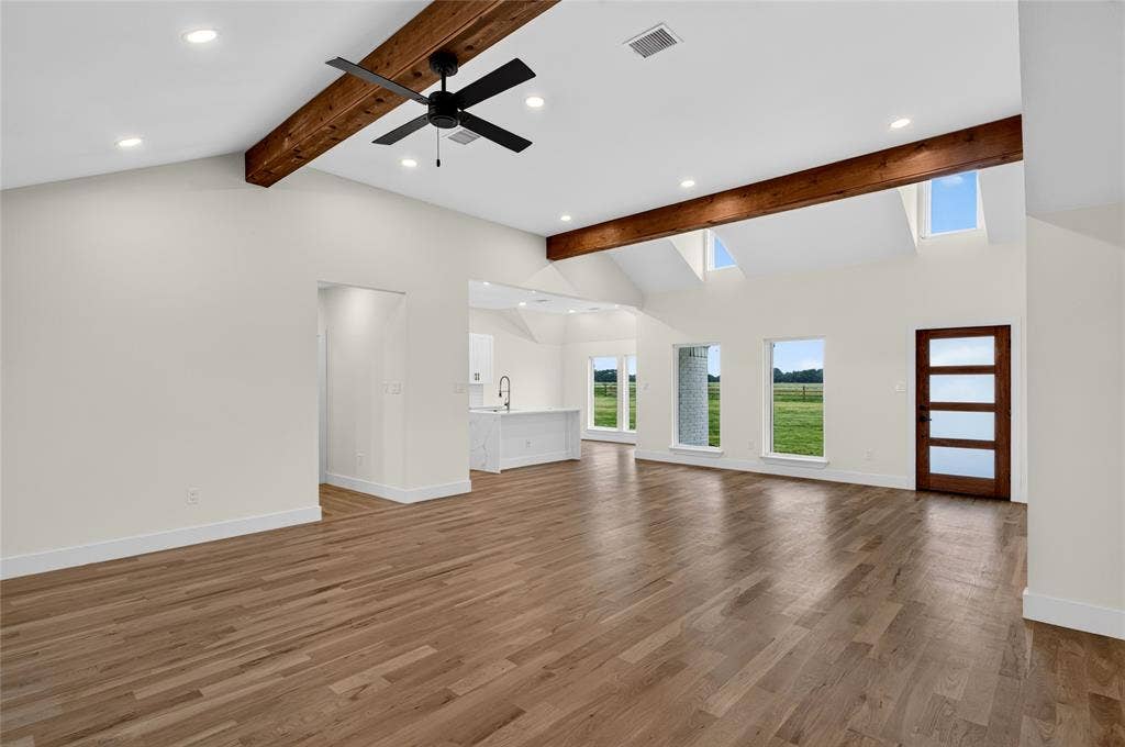15166 FM 3133, Anna, TX 75409 Spacious living area featuring wood-finish flooring, exposed ceiling beams, a contemporary ceiling fan, recessed lighting, and multiple windows