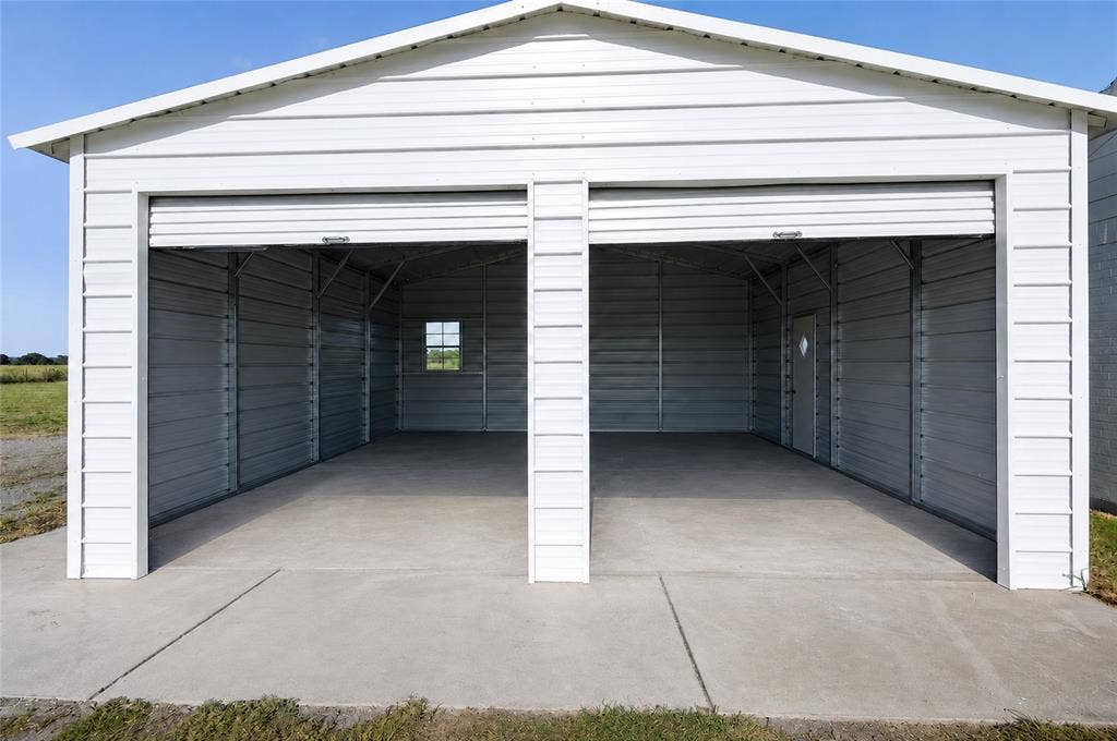 15166 FM 3133, Anna, TX 75409 White metal two-bay garage structure with roll-up doors, concrete flooring, and interior metal framing