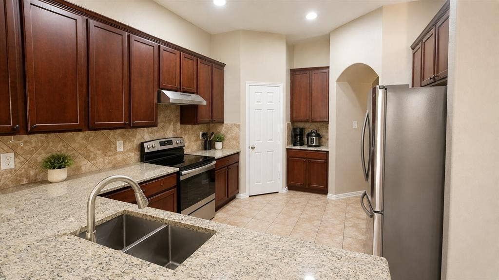 7004 Canyonbrook Drive, Plano, TX 75074 Kitchen featuring granite countertops, wood cabinetry, stainless steel appliances, a tile backsplash, and recessed lighting