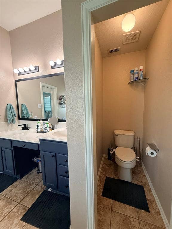 7004 Canyonbrook Drive, Plano, TX 75074 Dual vanity with white countertops and dark blue cabinetry, featuring a large mirror with integrated lighting
