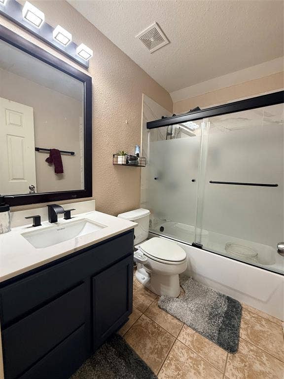 7004 Canyonbrook Drive, Plano, TX 75074 Bathroom featuring a dark vanity with a white countertop and rectangular undermount sink, matte black faucet, framed mirror, and a shower-tub combination with sliding glass doors