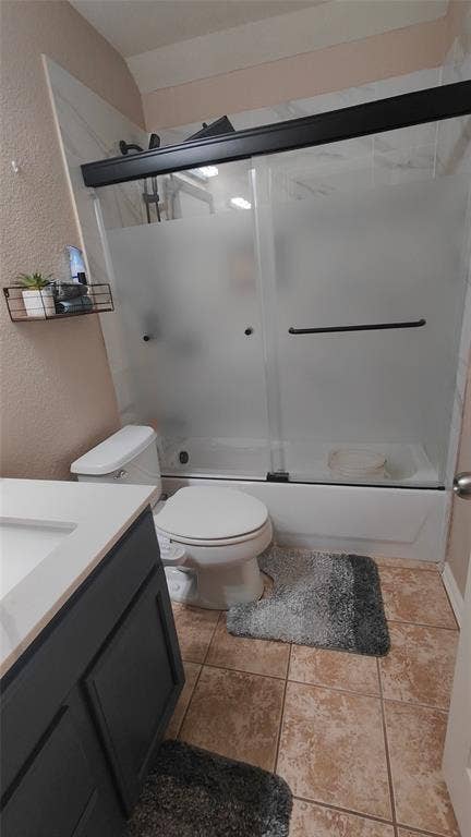 7004 Canyonbrook Drive, Plano, TX 75074 Built-in vanity with integrated sink, coordinating toilet, and a combination shower/bathtub with sliding frosted glass doors