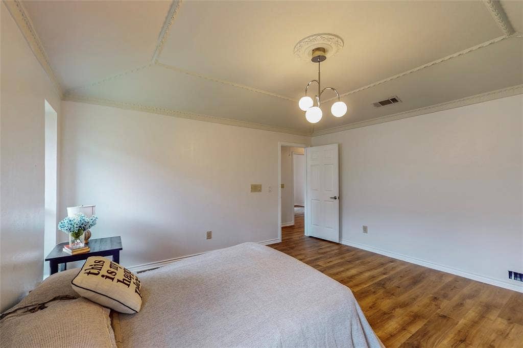 Wood-finish flooring, white walls, decorative ceiling molding, and a modern ceiling light fixture