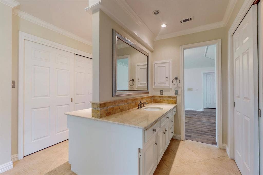 Dual vanity with a stone countertop and integrated sink, framed mirror, recessed lighting, and a tiled backsplash