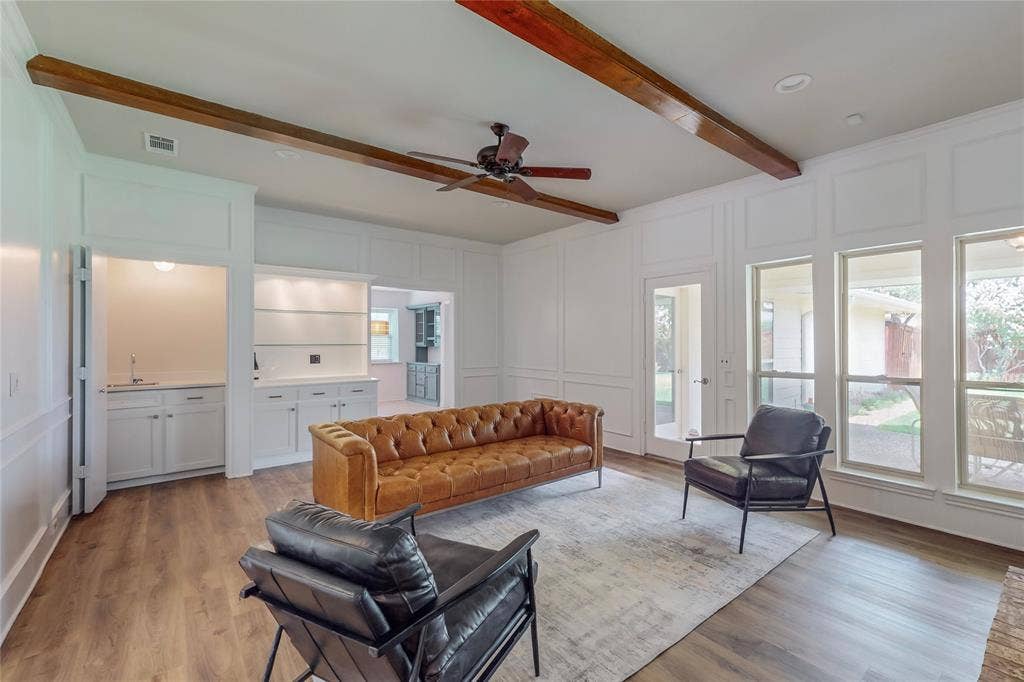 Recessed lighting, wood-finish flooring, exposed ceiling beams, built-in cabinetry, and a beverage station with a sink