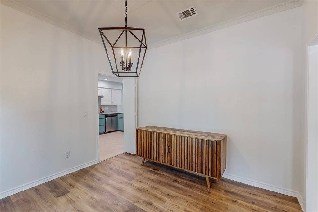 Crown molding, wood-finish flooring, and a modern geometric chandelier