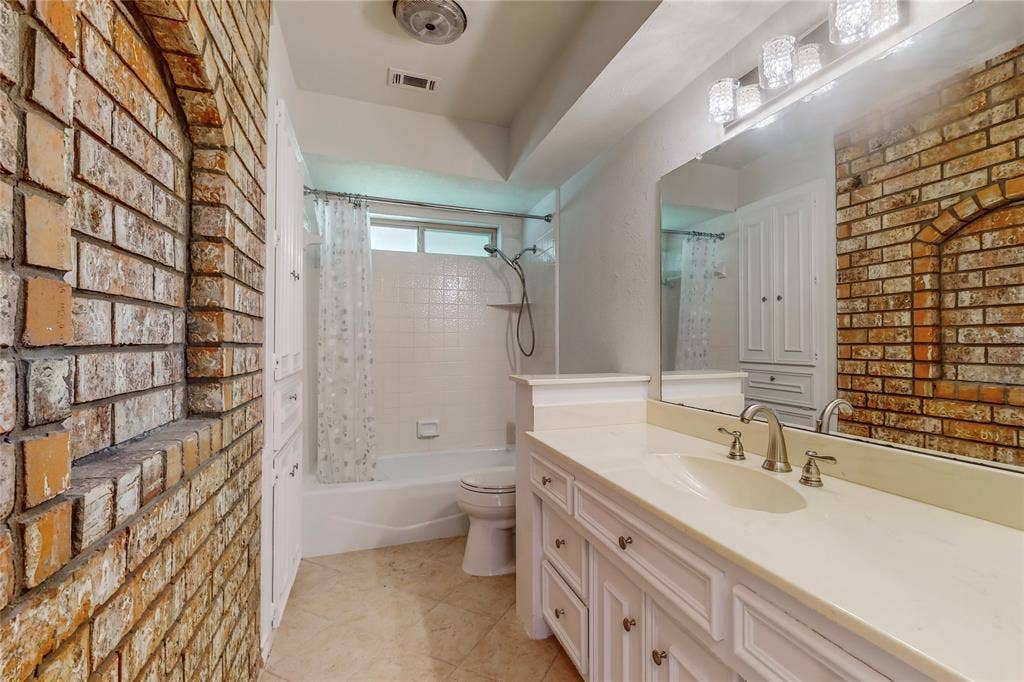 White vanity with integrated sink, brushed nickel faucet, large mirror, and four-light vanity fixture