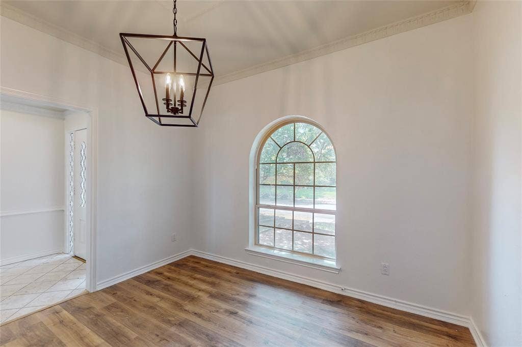 Wood-finish flooring, an arched window, and a geometric chandelier with candelabra bulbs