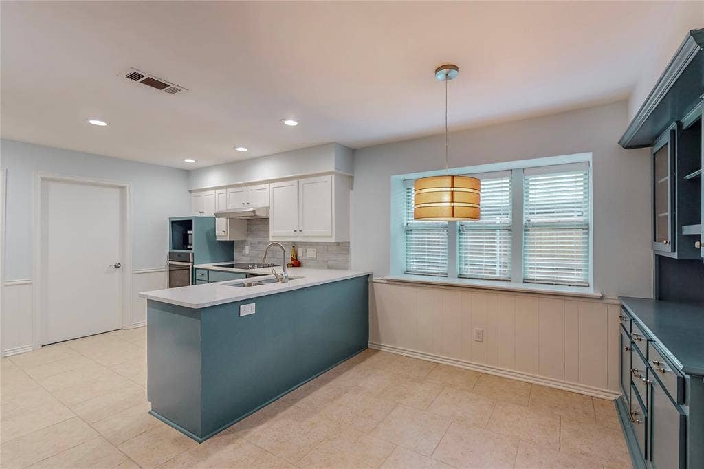 Kitchen featuring a center island, white cabinetry, integrated stainless steel appliances, and tile flooring