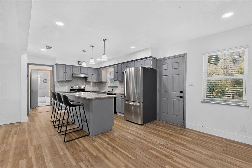Kitchen featuring gray cabinetry, stone-surface countertops, stainless steel refrigerator, recessed lighting, and wood-finish flooring