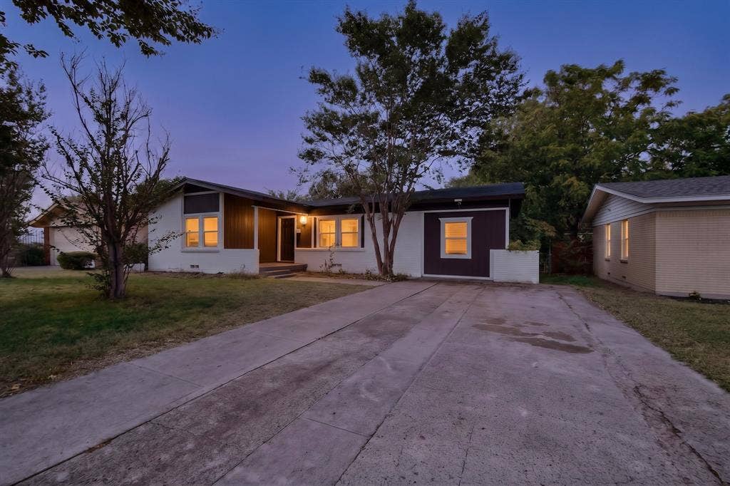 Mid-century ranch exterior featuring a multi-tone facade, concrete driveway, and mature landscaping