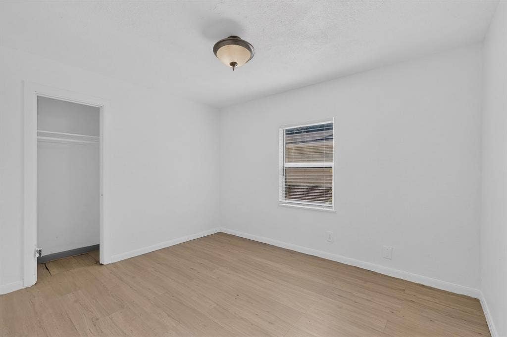 Room featuring wood-finish flooring, a single-window configuration, a recessed closet with an integrated rod, and a flush-mount ceiling light fixture