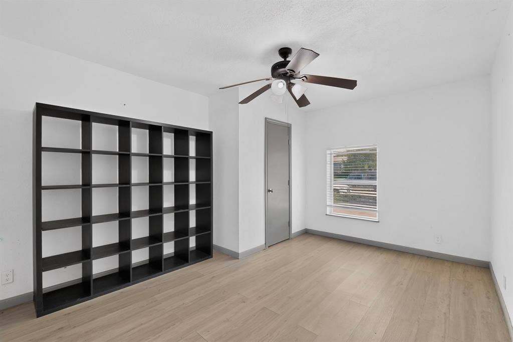 Room featuring wood-finish flooring, a ceiling fan with integrated lighting, and a single-hung window with blinds
