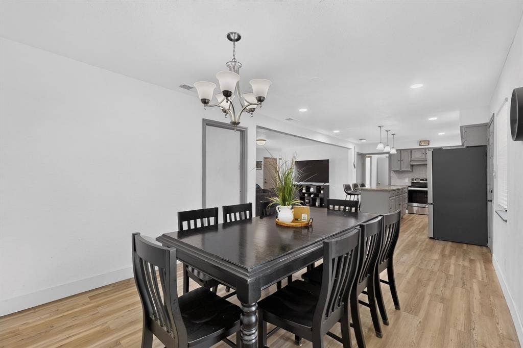 Dining area featuring wood-finish flooring, a multi-arm chandelier with frosted glass shades, and recessed ceiling lighting