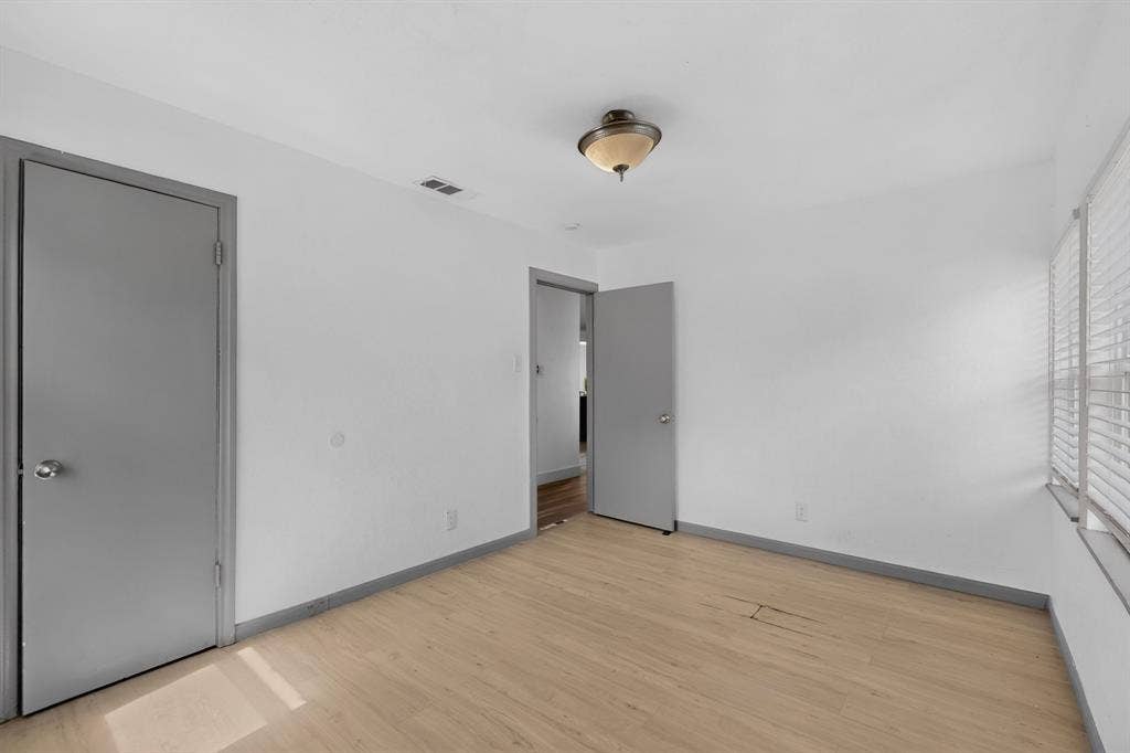 Neutral-toned walls, light-toned wood-finish flooring, grey interior doors, and a flush-mount dome light fixture