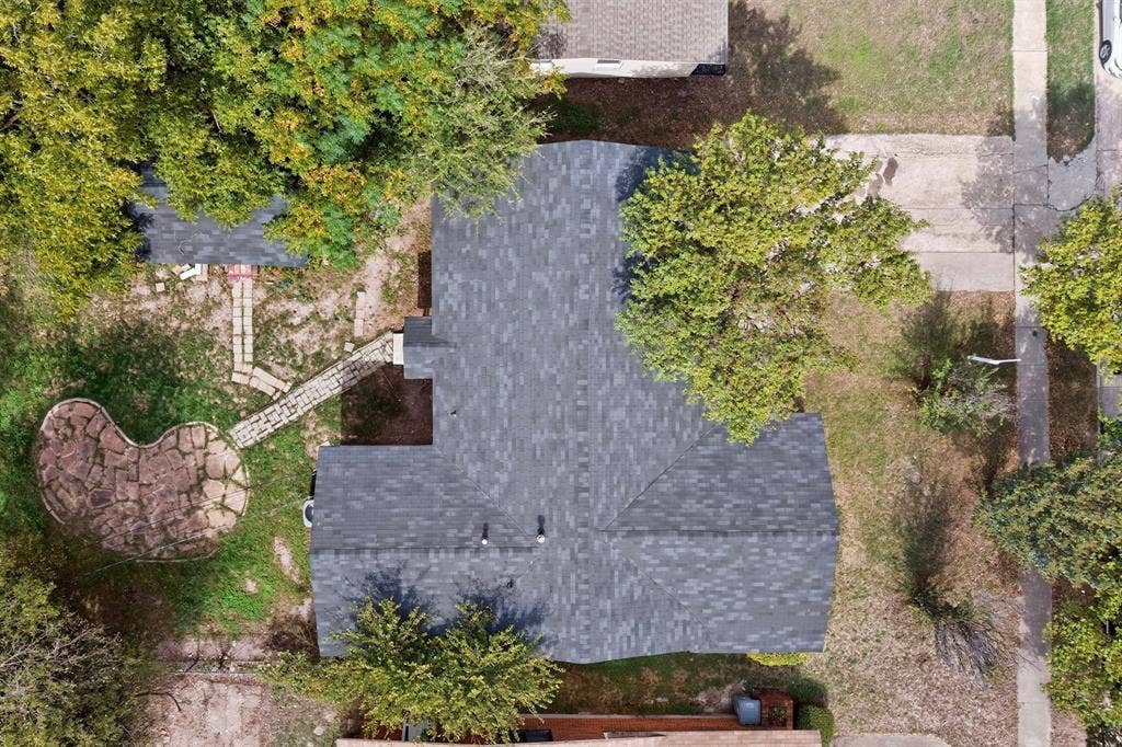 Aerial perspective of the property featuring a shingled roof, a flagstone patio, and a stone-paver walkway