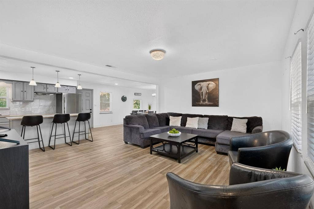 Open-concept interior featuring wood-finish flooring, a kitchen breakfast bar with pendant lighting, and recessed ceiling lighting