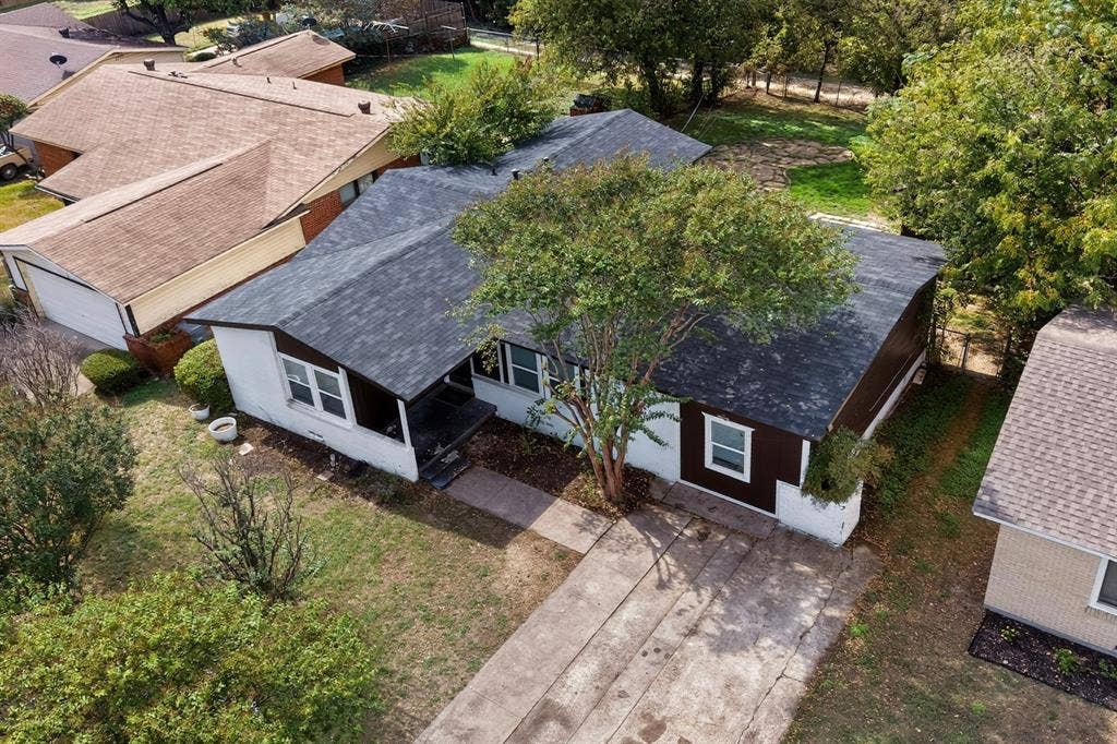 Single-story exterior featuring multi-textured siding, asphalt shingle roofing, concrete driveway, and mature landscaping