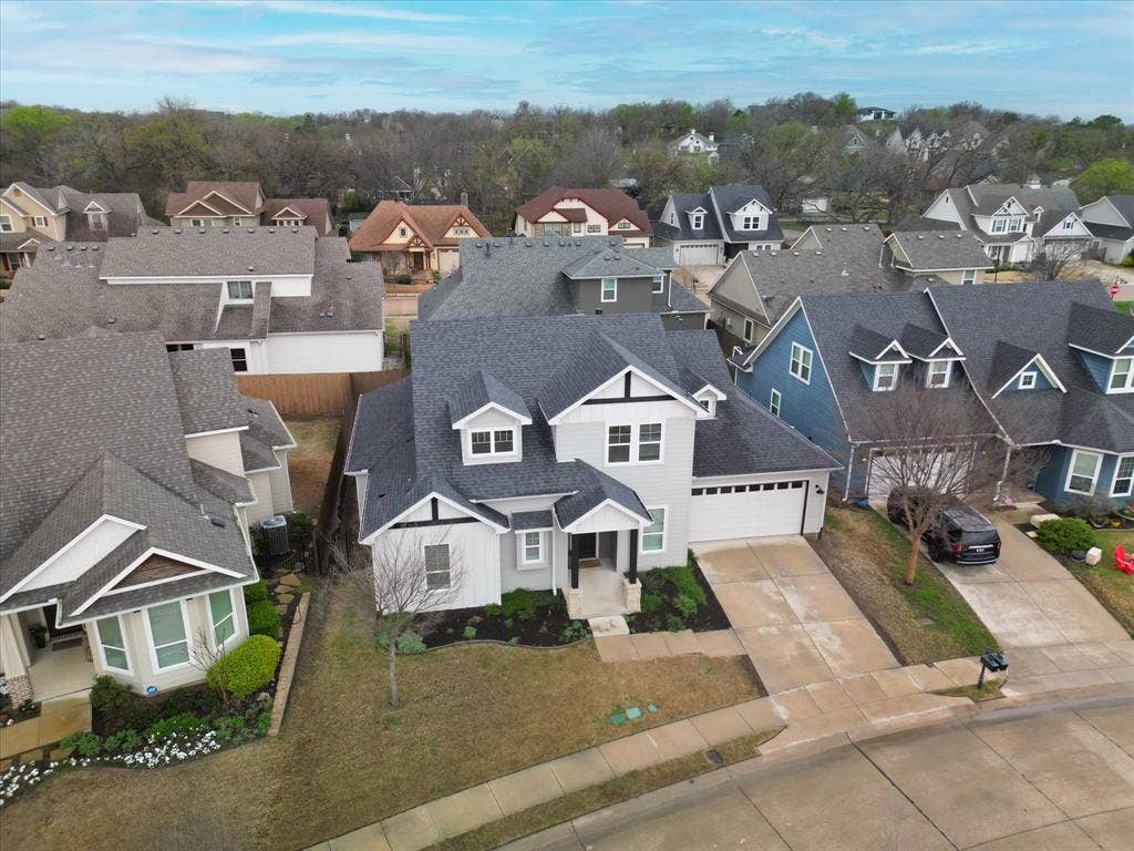 Two-story residence with a light gray exterior, dark gray shingle roof, and a two-car garage