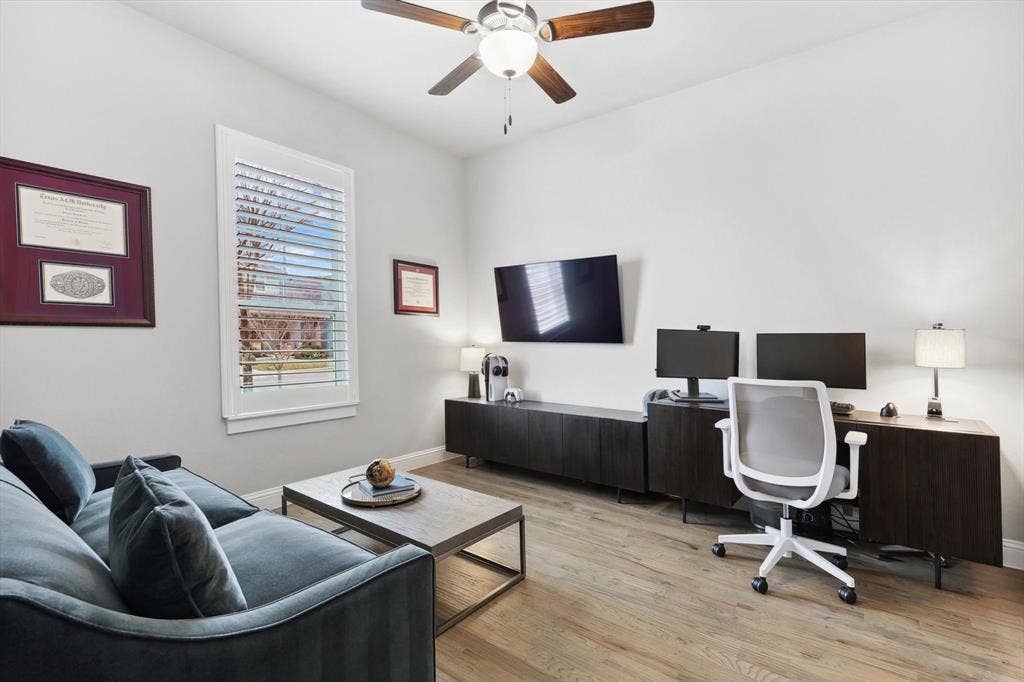 Wood-finish flooring, white walls, and a ceiling fan with integrated lighting