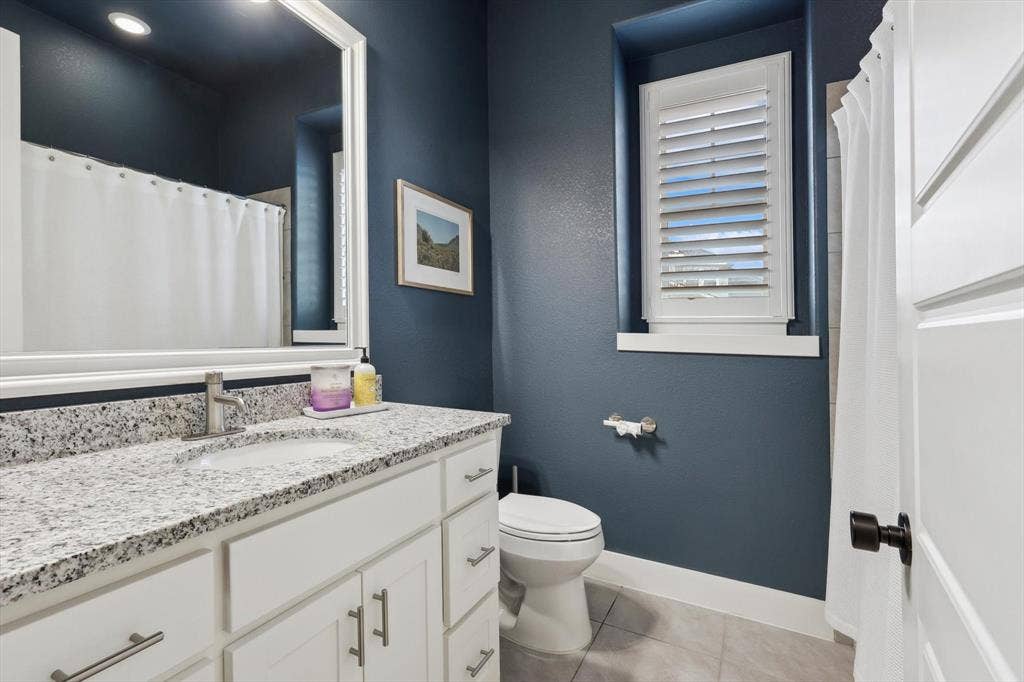 White shaker vanity with a granite countertop, undermount sink, and brushed nickel faucet