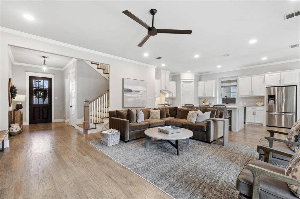 Open-concept living space featuring wood-finish flooring, recessed lighting, and a dark wood entry door
