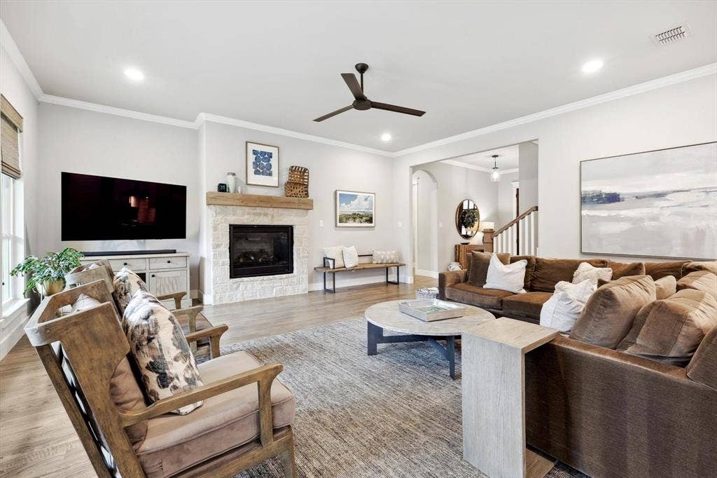Spacious living area featuring wood-finish flooring, a stone fireplace with a substantial wood mantle, and recessed lighting