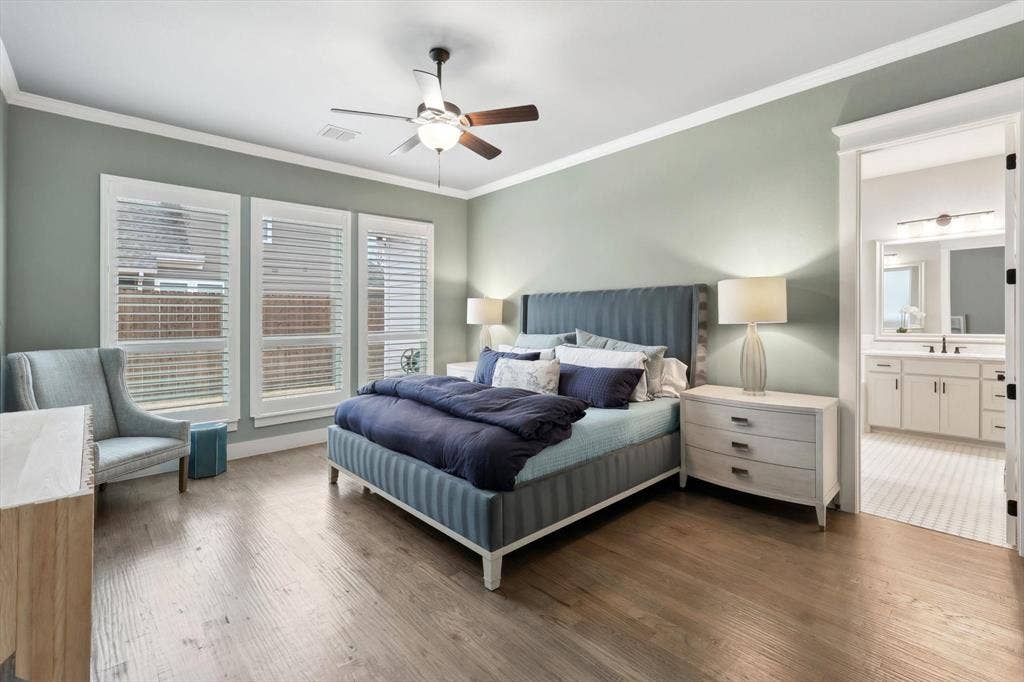 Hardwood-finish flooring, three large windows with plantation shutters, ceiling fan, and crown molding