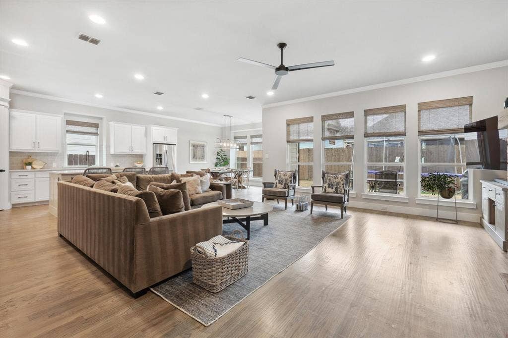 Open-concept living area with light wood-finish flooring, recessed lighting, and a ceiling fan