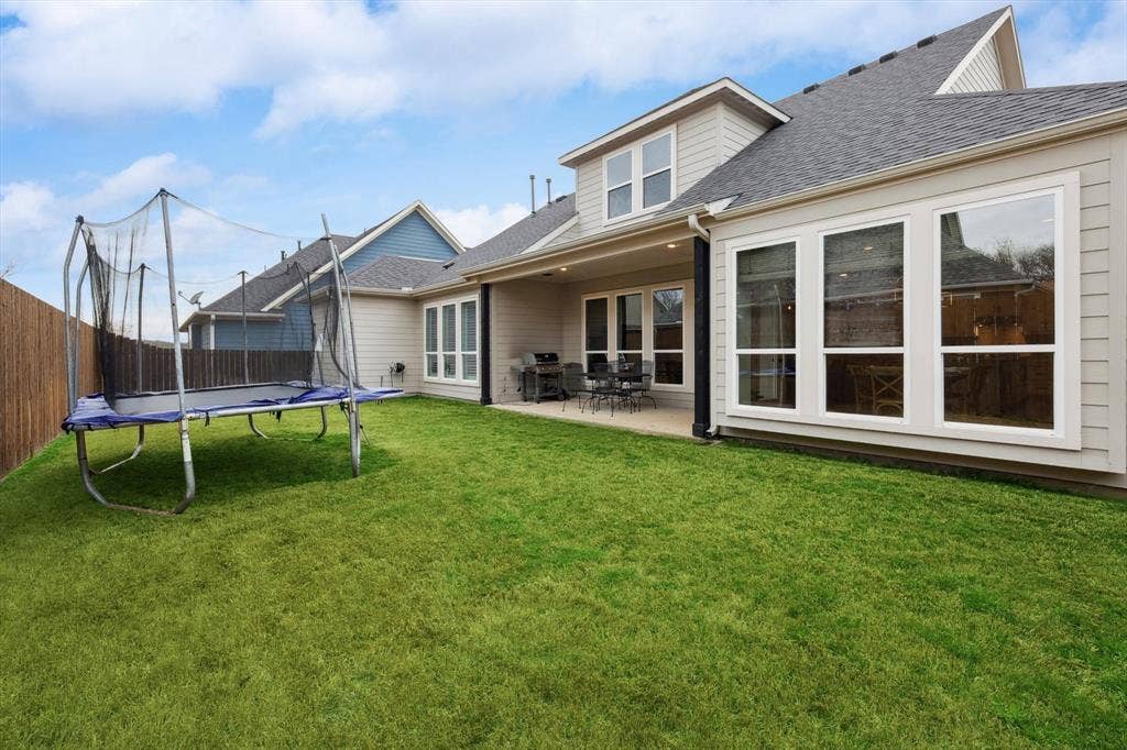 Expansive backyard featuring a manicured lawn, a covered patio, and a privacy fence