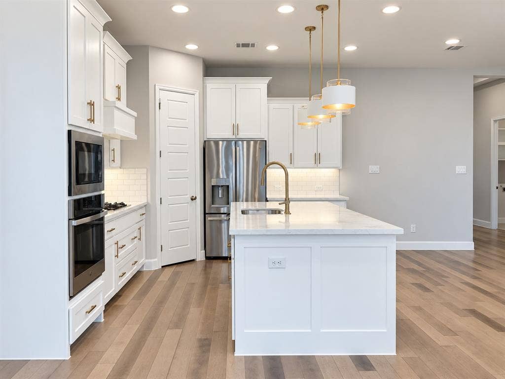 2234 Somercrest Place, Midlothian, TX 76065 Kitchen featuring light wood-finish flooring, white cabinetry with gold-tone hardware, a center island with a sink and pendant lighting, stainless steel appliances