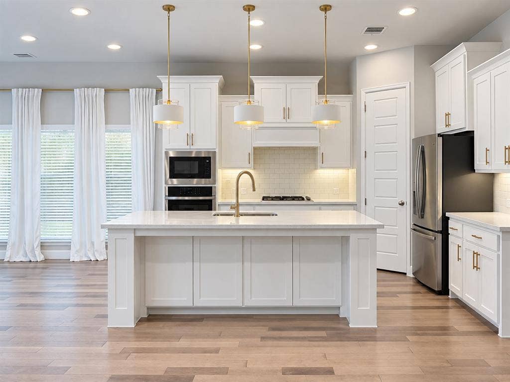 2234 Somercrest Place, Midlothian, TX 76065 Kitchen featuring a large center island, white cabinetry with gold-tone hardware, stainless steel appliances, and wood-finish flooring
