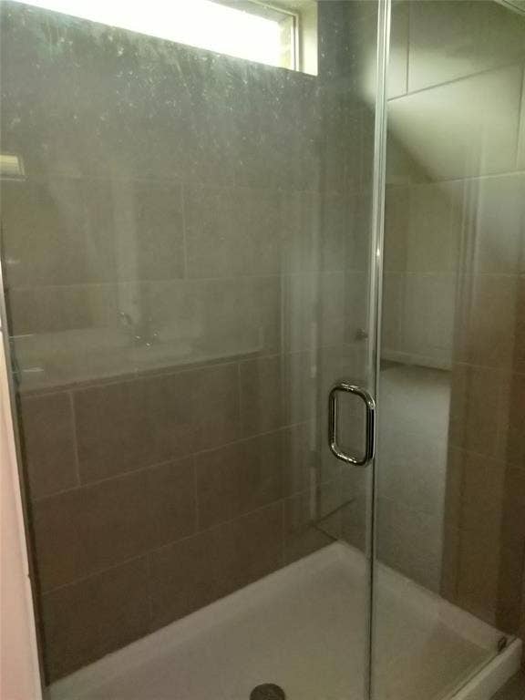 601 Willet Drive, McKinney, TX 75069 Frameless glass shower enclosure with a chrome handle, complemented by large format wall tiling and a white shower pan