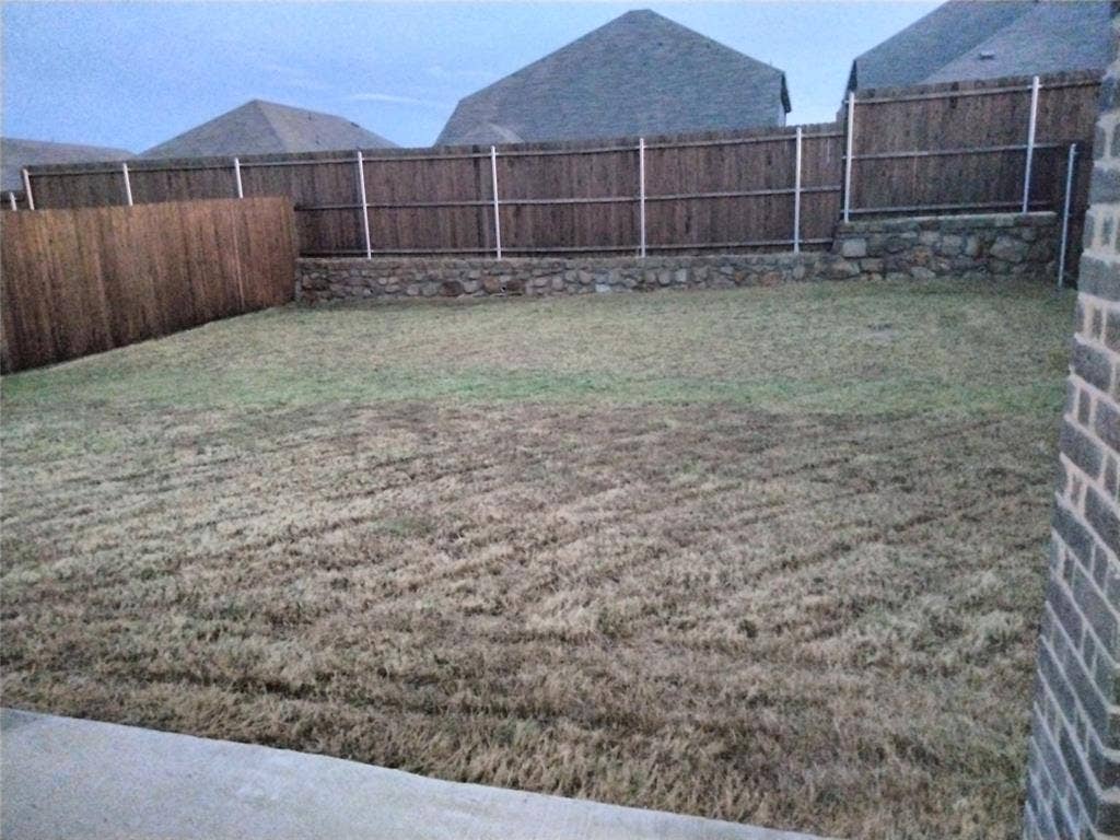 601 Willet Drive, McKinney, TX 75069 Expansive backyard space with a wood privacy fence and a stone retaining wall