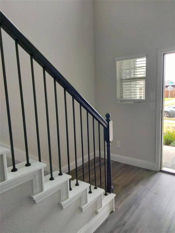 601 Willet Drive, McKinney, TX 75069 Staircase with black metal balusters and white risers, carpeted treads, wood-finish flooring, and white window blinds