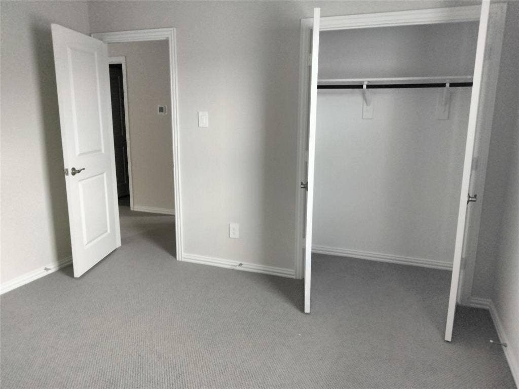 601 Willet Drive, McKinney, TX 75069 Neutral-toned wall paint, light gray carpet flooring, white paneled doors, and a closet with a hanging rod