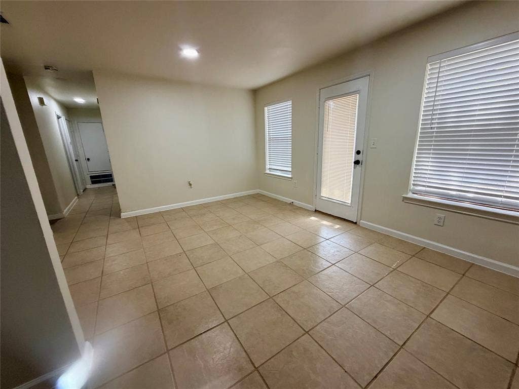 Ceramic tile flooring throughout, featuring a glass-paneled exterior door and two windows with horizontal blinds