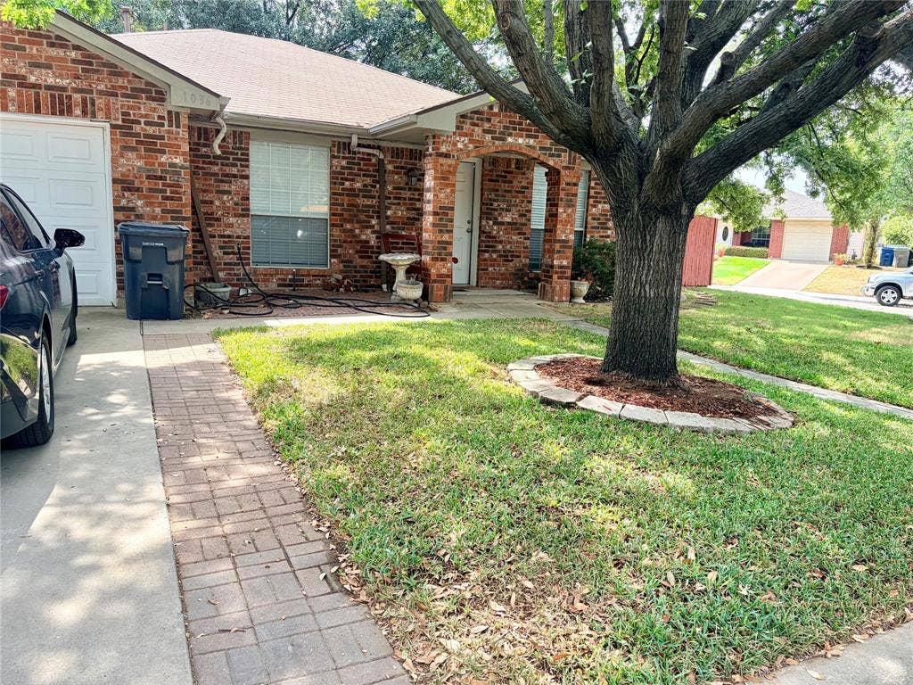 Brick exterior with an arched entryway, attached garage, and a concrete driveway