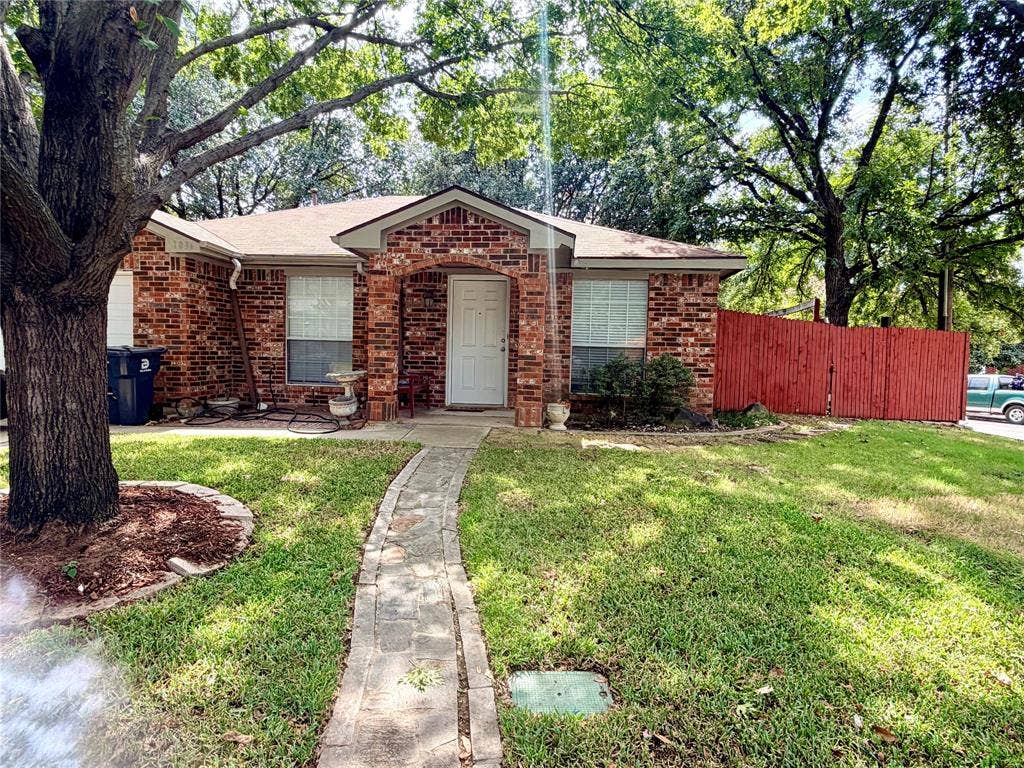 Brick facade with a covered entry, arched details, and a concrete paver walkway