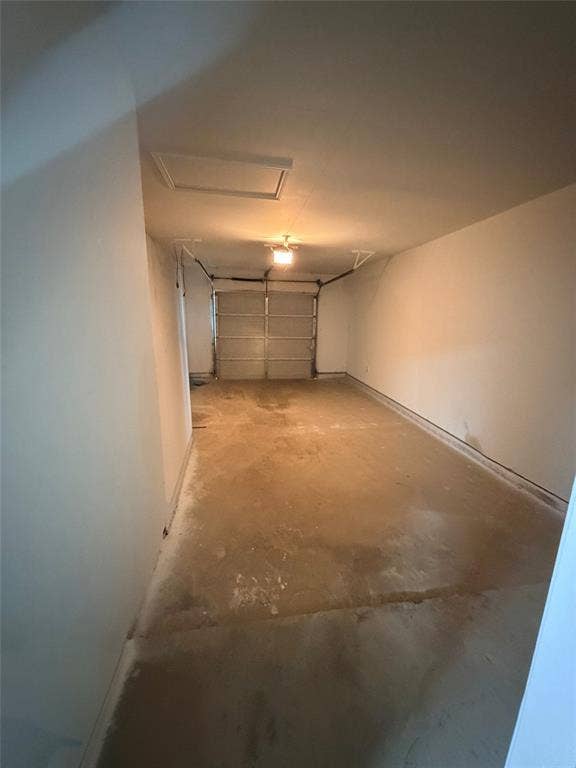 Concrete flooring with a white overhead garage door and an access panel