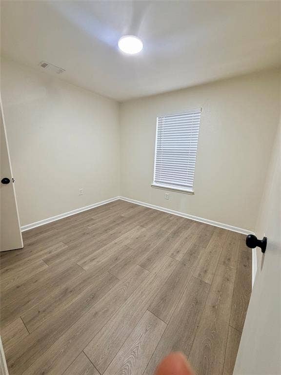 Neutral-toned walls, wood-finish flooring, recessed ceiling light, and window with horizontal blinds