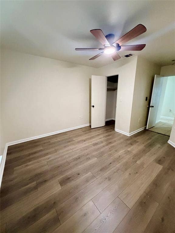 Wood-finish flooring with a ceiling fan featuring integrated lighting