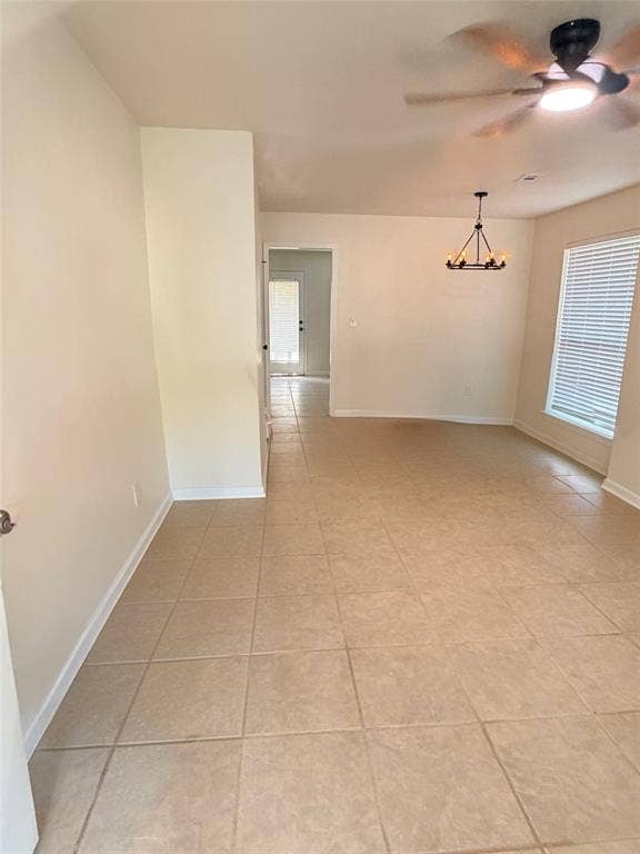 Neutral-toned tile flooring, overhead ceiling fan, and modern chandelier