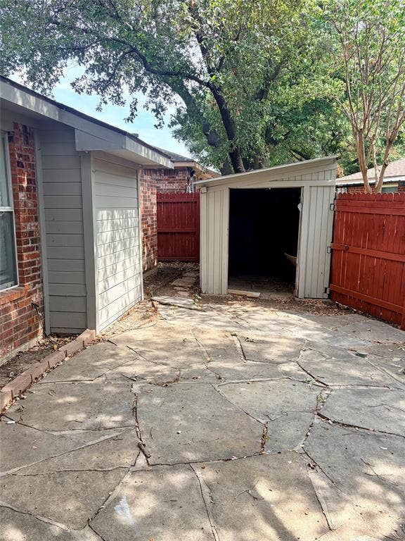 Concrete patio with flagstone-style patterning, adjacent to a storage shed with a sloped roof