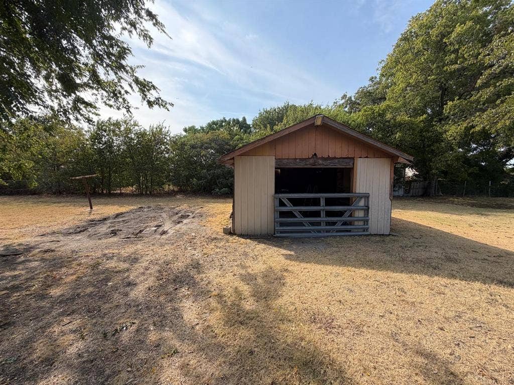 2928 Almeta Lane, McKinney, TX 75069 Outbuilding with a wood-finish facade and light-toned siding, featuring a metal gate and a pitched roof