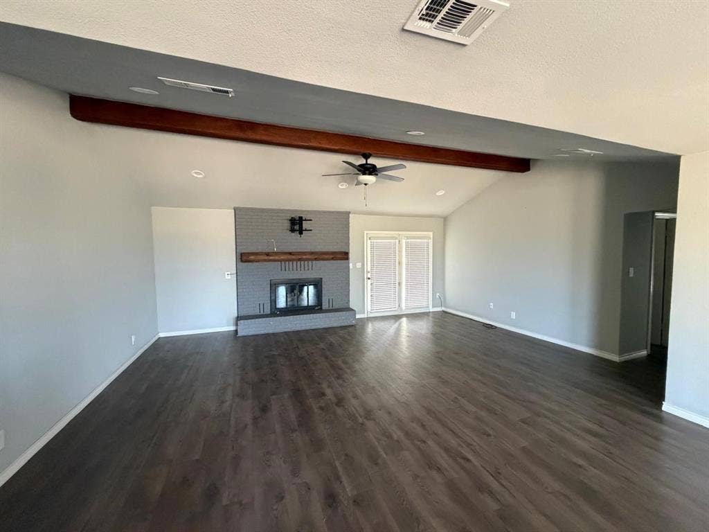 2928 Almeta Lane, McKinney, TX 75069 Vaulted ceiling with an exposed wood beam, wood-finish flooring, brick fireplace with a wood mantel, and double French doors
