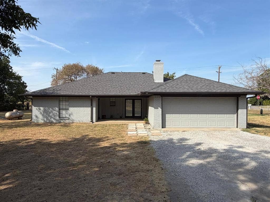 2928 Almeta Lane, McKinney, TX 75069 Grey brick exterior with a dark shingled roof, attached two-car garage, and a covered entry