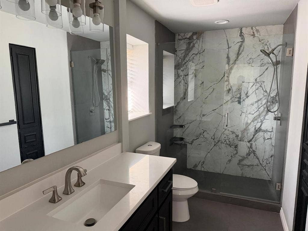 2928 Almeta Lane, McKinney, TX 75069 Custom glass-enclosed shower with large format marble-look tile, fixed and handheld showerheads, and recessed shelving