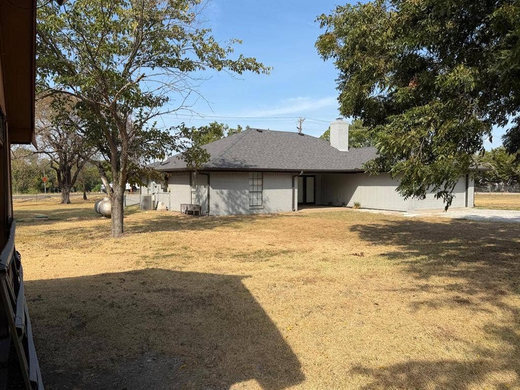 2928 Almeta Lane, McKinney, TX 75069 Exterior featuring a gray-toned facade, dark shingle roofing, and a prominent chimney structure